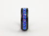 Side view of black tungsten ring with purple-blue crushed opal inlay on white background.