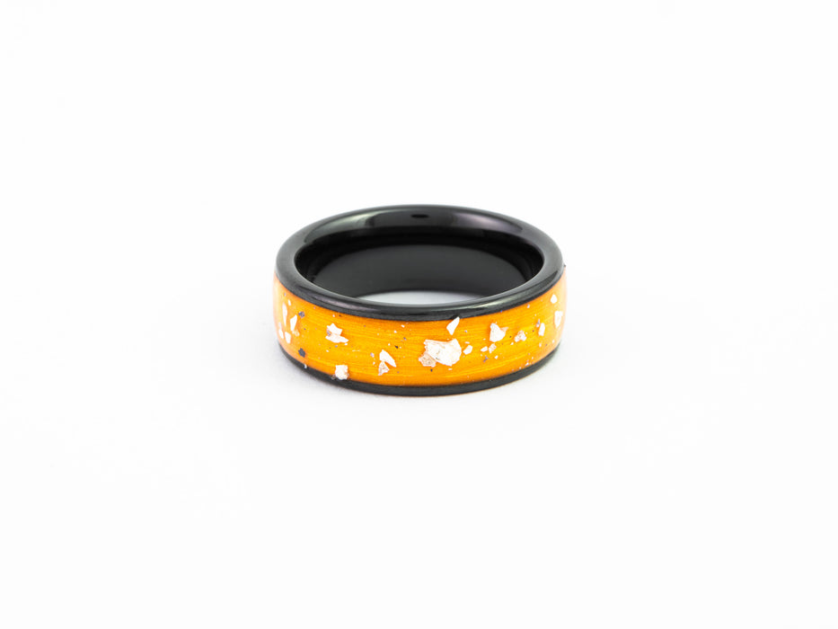 Top-down view of the Black Band Ring showing the orange resin and reflective Mother-of-Pearl flake inlay detail.