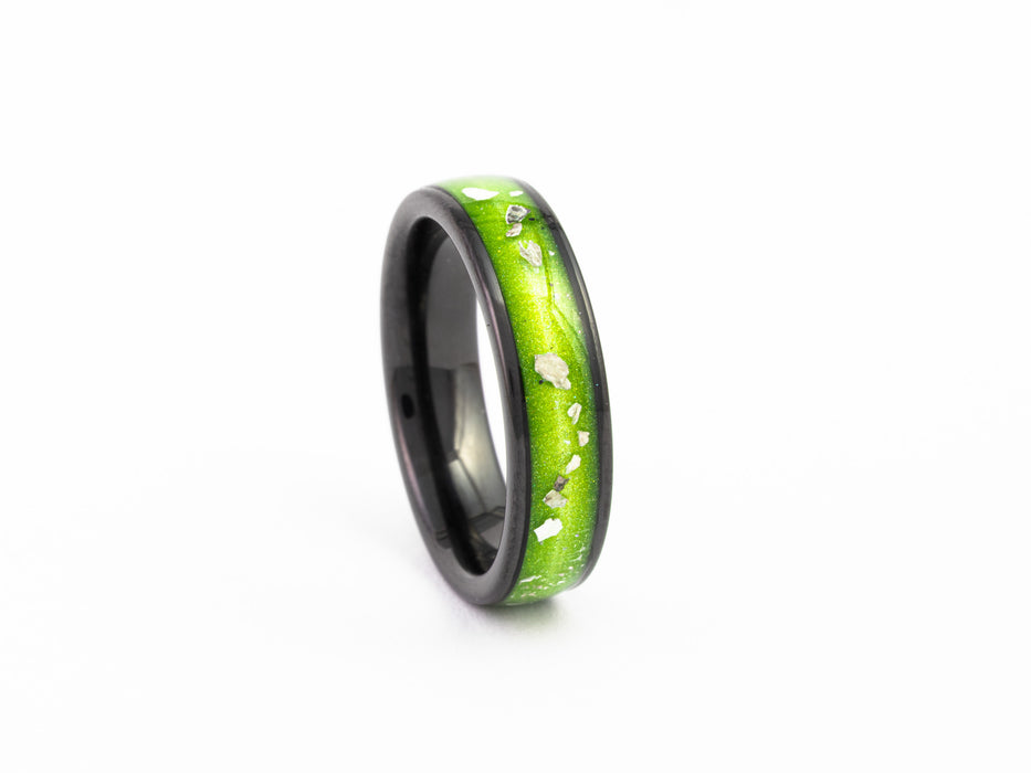 Angled view of the narrow Black Ceramic Ring with bright lime green resin and silver leaf flakes.
