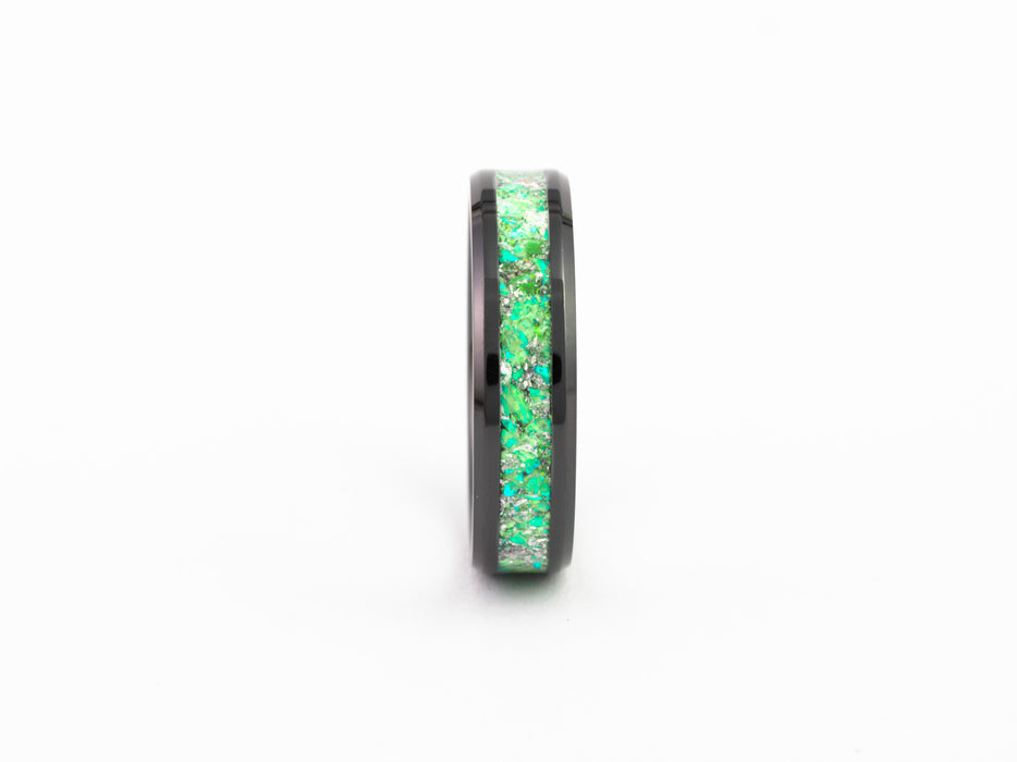 Side view of the Black Ceramic Ring detailing the bright green fire opal flake inlay on white background.