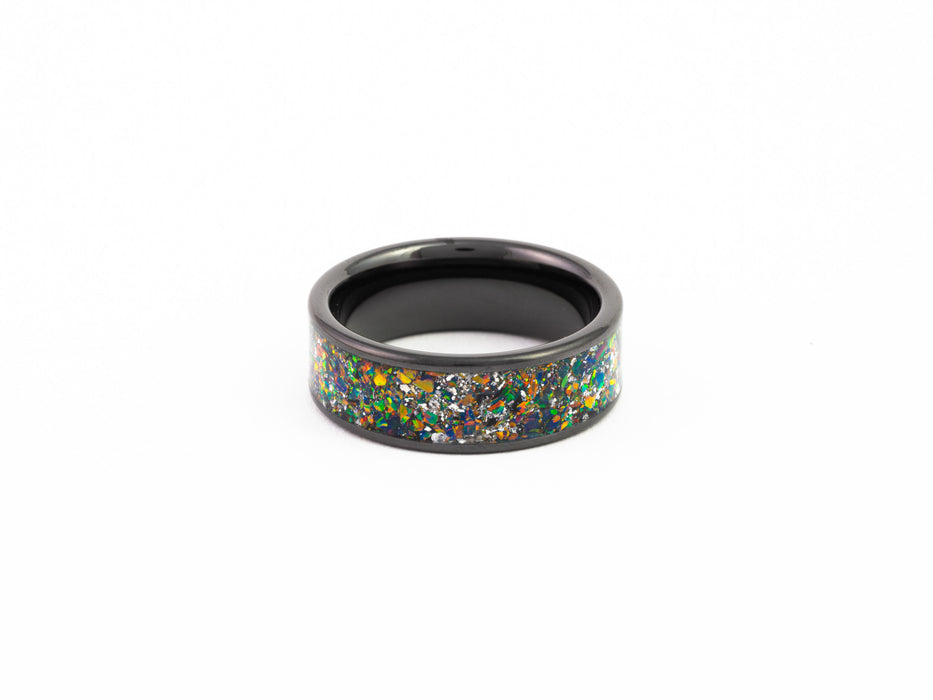 Top view of the Black Ceramic Ring showcasing the wide dark nebula-style multicolored fire opal inlay and silver flakes.