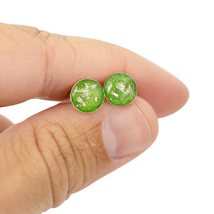Pair of sterling silver stud earrings with bright green opal resin inlays, held between two fingers for scale.