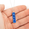 Sterling silver rectangular bar pendant with blue resin and silver flakes, shown worn in the palm.