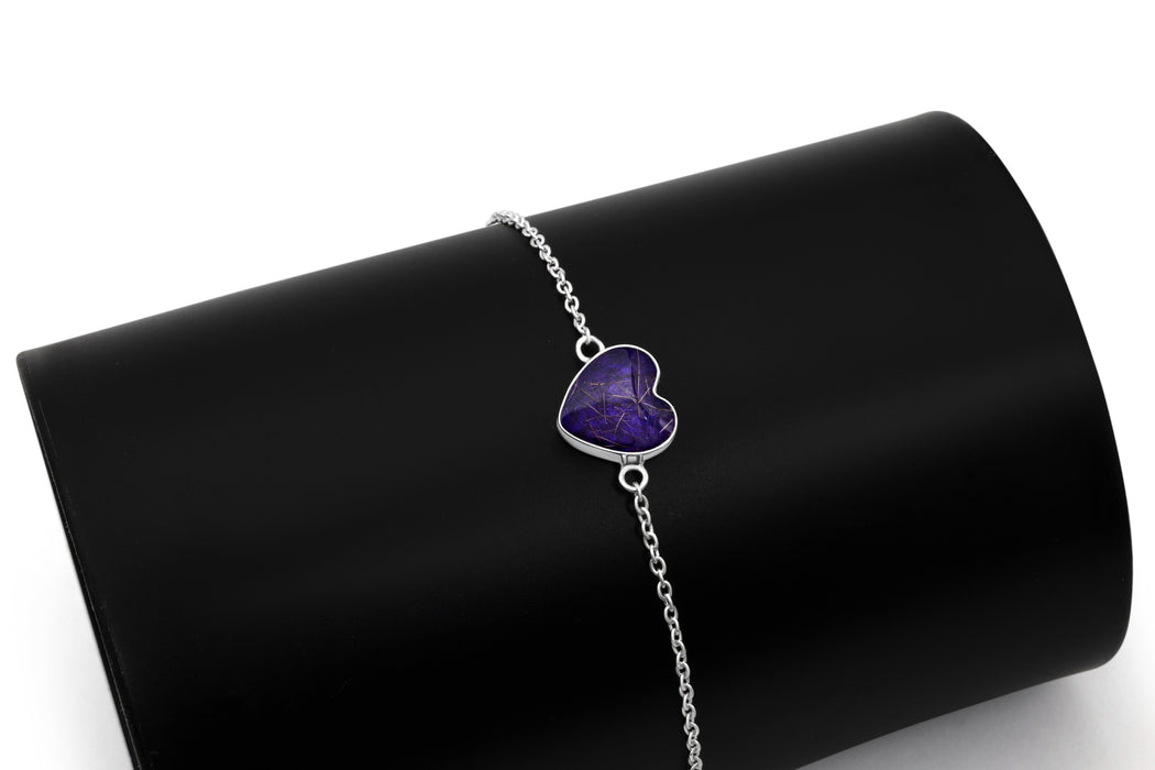Sterling silver chain bracelet with a deep purple resin heart charm, displayed on a black cylindrical stand.