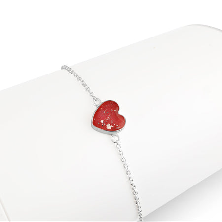 Silver chain bracelet displayed on a white stand, featuring a heart-shaped charm inlaid with bright red and pink opal resin.