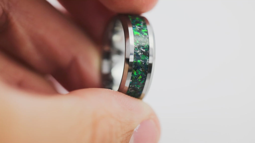 Close-up video of a silver tungsten ring with multicolored opal inlay held in hand, slowly rotated to show details.