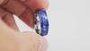Close-up video of the silver tungsten ring with blue inlay and white speckles, held in hand and slowly rotated to show details.