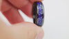 Close-up video of the black tungsten ring with purple-blue crushed opal inlay, held in hand and slowly rotated.