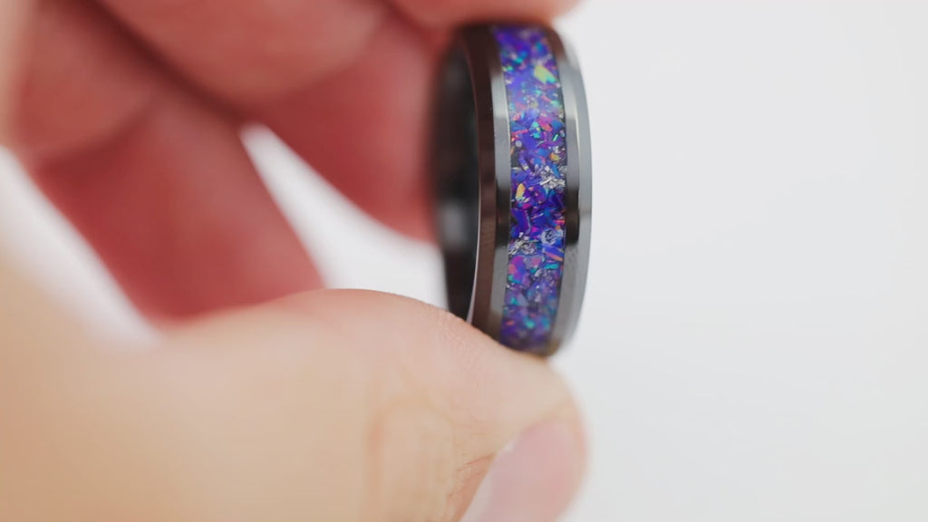 Close-up video of the black tungsten ring with purple-blue crushed opal inlay, held in hand and slowly rotated.